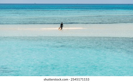 A man in a wetsuit walks on a sandbank among the beautiful water of the Red Sea in Egypt - Powered by Shutterstock