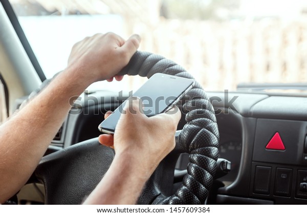 A man at the wheel holding a smartphone in\
his hand, violates traffic rules. The concept of an accident, a\
traffic violation, the phone at the\
wheel.