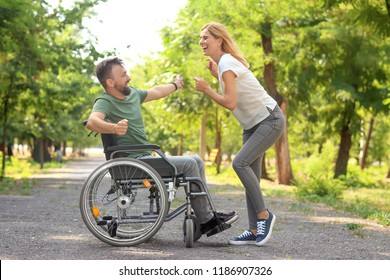 Man in wheelchair with beautiful woman dancing outdoors - Powered by Shutterstock