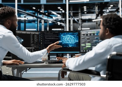 Man in wheelchair and coworker setting up data center gear needed to run artificial intelligence and machine learning. IT expert with disability and colleague in inclusive server room using AI tools
