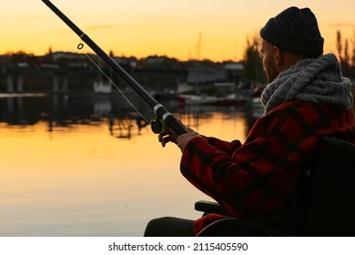 Man In Wheelchair Fishing On River At Sunset