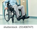 A man in a wheelchair navigates through the wide, open spaces of a modern hospital corridor, highlighting the importance of both mobility and accessibility in healthcare environments