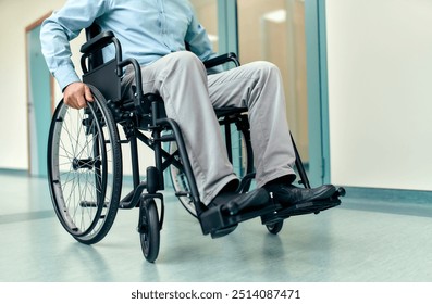 A man in a wheelchair navigates through the wide, open spaces of a modern hospital corridor, highlighting the importance of both mobility and accessibility in healthcare environments - Powered by Shutterstock