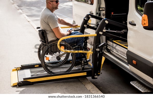 A man in a wheelchair on a lift of a vehicle\
for people with disabilities