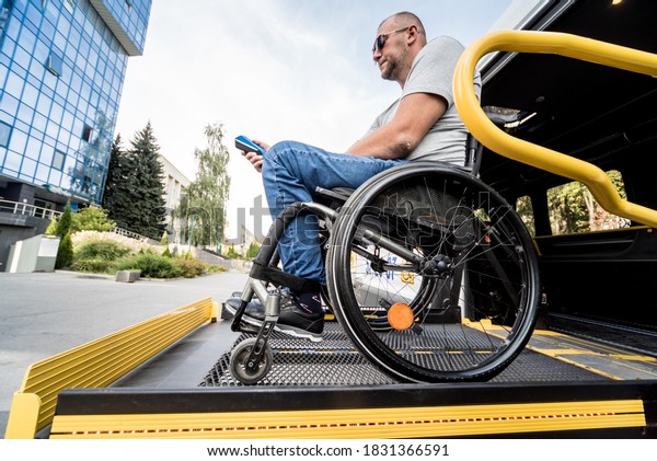 A man in a wheelchair on a lift of a vehicle\
for people with disabilities