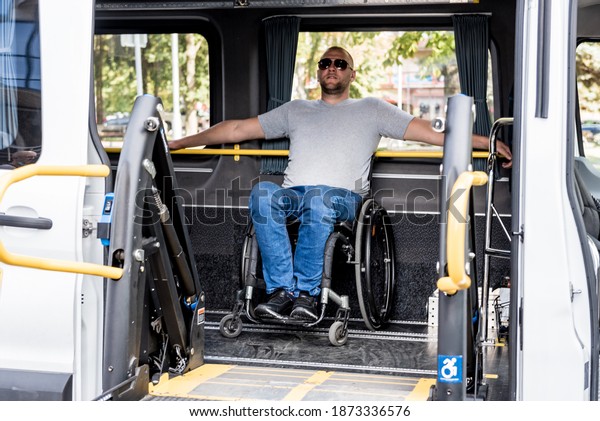 A man in a wheelchair on a lift of a vehicle
for people with disabilities