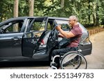 A man in a wheelchair is positioned beside a car, preparing for a transfer. 