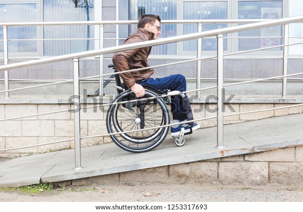 Man in a\
wheelchair use a wheelchair\
ramp.