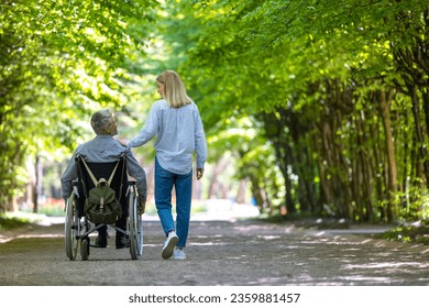 Man in wheelchair walking at park with his wife. - Powered by Shutterstock