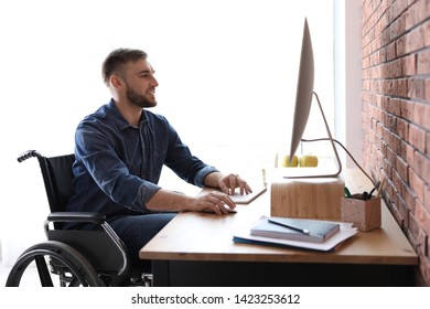 Man In Wheelchair Working With Computer At Table Indoors