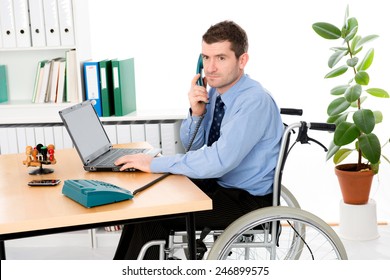 Man In Wheelchair Is Working In The Office