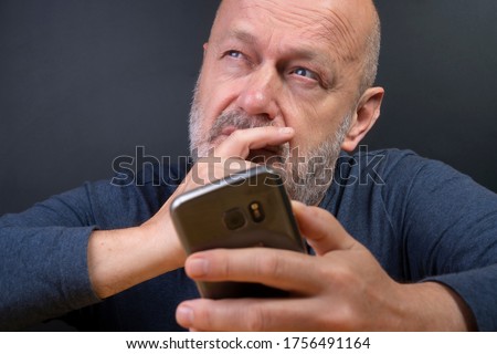 a man while reflecting before retweeting a message on his mobile phone