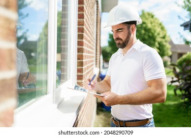 A man with a white hard hat holding a clipboard, inspect house - Shutterstock ID 2048290709