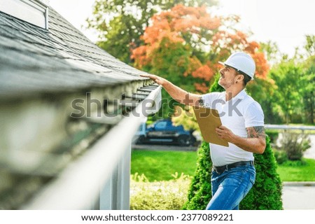 A Man with a white hard hat holding a clipboard, inspect house roof