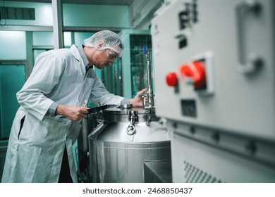 A man in a white lab coat is working on a machine. The machine is large and has a red button on it - Powered by Shutterstock