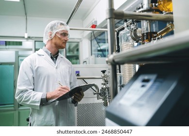 A man in a white lab coat is writing on a clipboard in front of a machine. Concept of focus and concentration as the man takes notes while working in a laboratory setting - Powered by Shutterstock