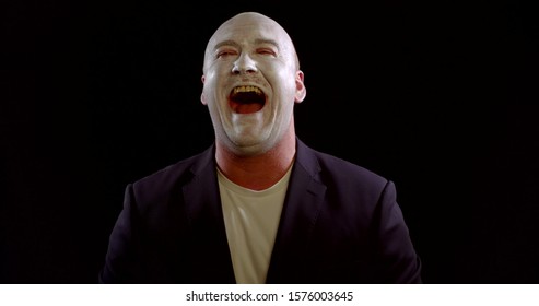 Man With White Makeup On Face Is Laughing Like A Joker In Black Background, Evil Uncontrollable Laughter