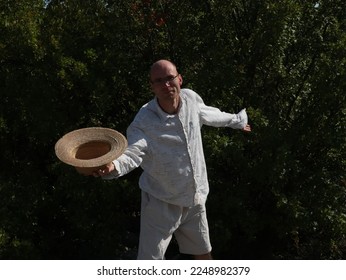 Man in white posing with a hat