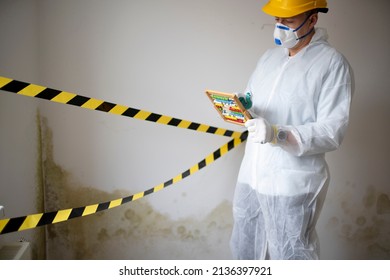 Man With White Protective Suit With Abacus Calculator, Slide Rule In Hand And Mouth Nose Mask In Front Of Yellow Black Barrier Tape In Front Of Wall With Mildew