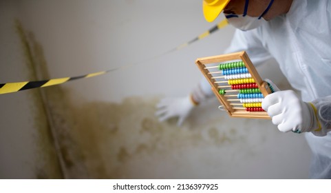 Man With White Protective Suit With Abacus Calculator, Slide Rule In Hand And Mouth Nose Mask In Front Of Yellow Black Barrier Tape In Front Of Wall With Mildew