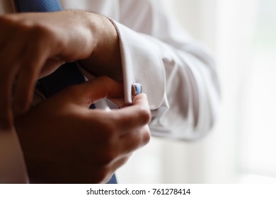 The man in the white shirt adjusts his cufflinks on the sleeves. Elegant fashion businessman fixing his cufflinks, closeup - Powered by Shutterstock