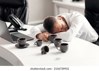 A Man In A White Shirt With His Head Bowed Over The Table Drank A Lot Of Coffee But Fell Asleep. A Lot Of Work