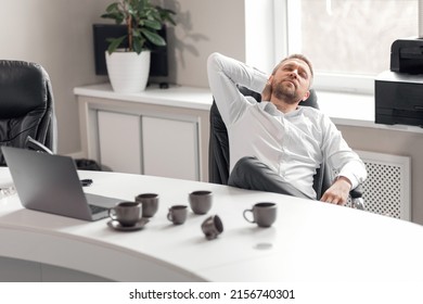 A Man In A White Shirt With His Head Bowed Over The Table Drank A Lot Of Coffee But Fell Asleep. A Lot Of Work