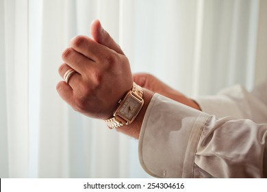 The Man In The White Shirt In The Window Wears A Gold Watch.