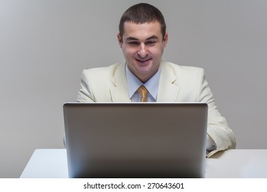 A man in a white suit sitting with a laptop. Makes hand gestures. Vivid emotions.