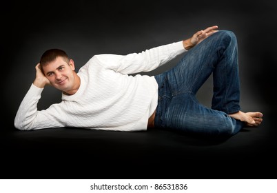 Man In A White Sweater Lying On A Black Background