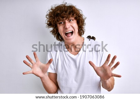 man in a white T-shirt with spider on a white background, male is screaming, frightened, Arachnophobia fear of spiders