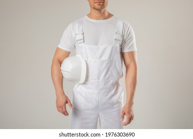 A Man In A White Work Uniform Holds A White Helmet In His Hands. Mock-up.