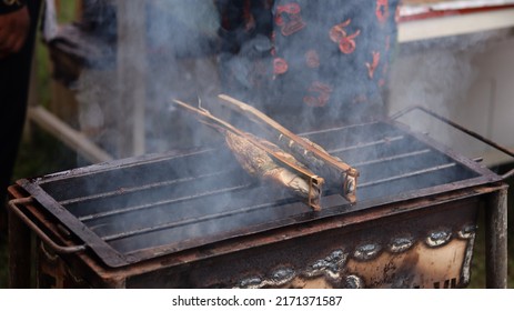 A Man Who Is Grilling Fish Traditionally Uses A Grill To Sell And See The Smoke. 