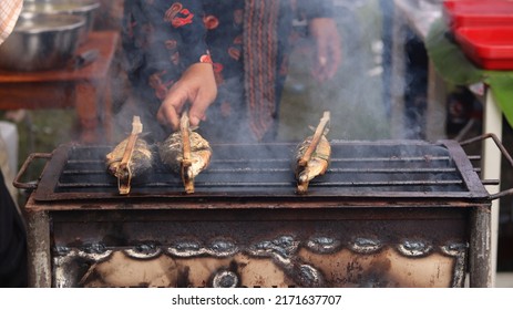 A Man Who Is Grilling Fish Traditionally Uses A Grill To Sell And See The Smoke. 