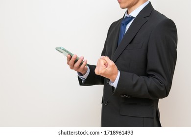 
				A man who makes a guts pose looking at a smartphone