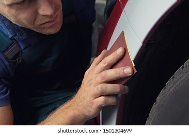 A man who sanding with a grinder and prepares the paint for the car in a car service. - Powered by Shutterstock