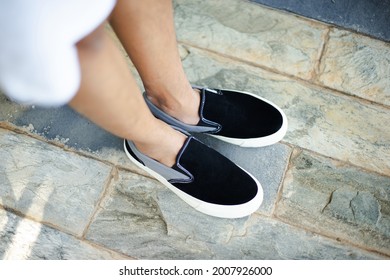 A man who is wearing black and white slip-on shoes that are comfortable for everyday wear.