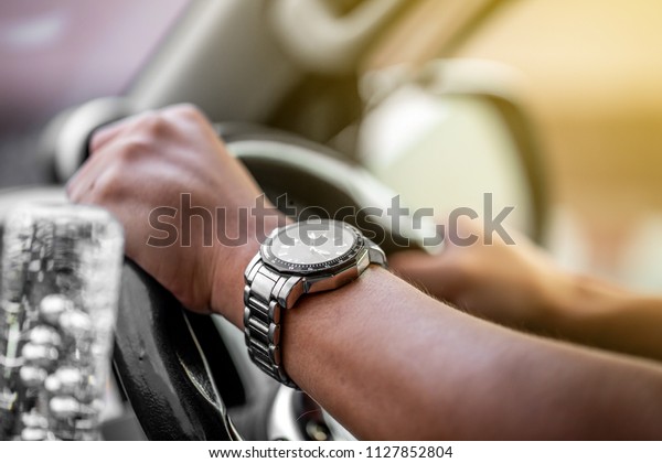 Man who wearing \
watch is driving vehicle while working or going to somewhere with\
flare from the outside. 