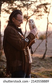 Man and wild bird over sunset sky in forest looking on each other Owl symbol of power, wisdom wealth, learning person in eye glasses, vision problems. Nature and human partnership, friendship