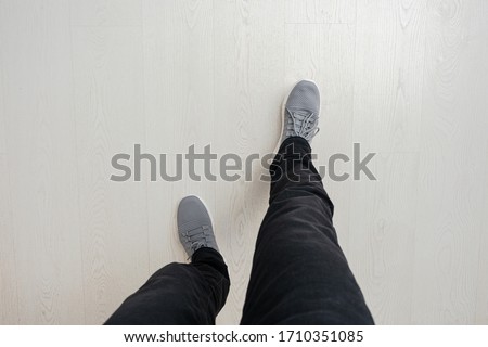 Man will take a step, wooden floor, feet in sneakers, close-up, top view, copy space