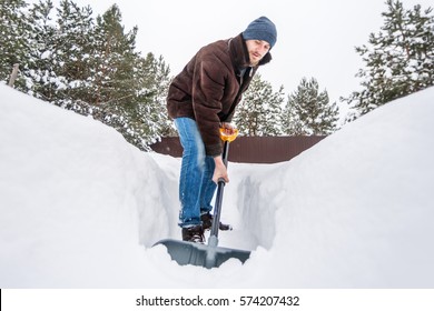 Man In Winter Clothes Cleans Snow Shovel On Courtyard