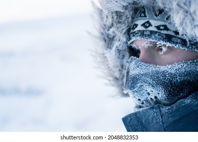 A man in winter clothes and a mask. Portrait of a traveler in the Arctic. Ice and snow on eyelashes, face and mask. Cold polar climate. Extreme travel and expeditions to the far North to the Arctic.