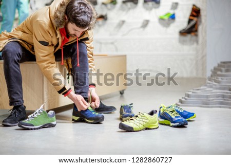 Man in winter jacket trying shoes for mountain hiking sitting in the fitting room of the modern sports shop ストックフォト © 