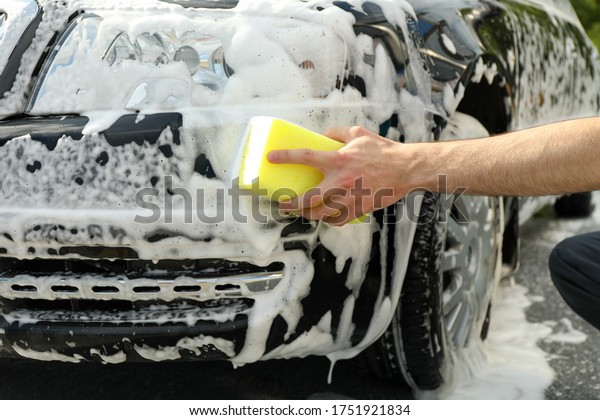 Man wipes the car with a sponge. Car wash. Clear\
car concept
