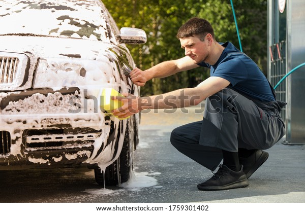 Man wipes the car with a sponge. Car wash. Clear\
car concept