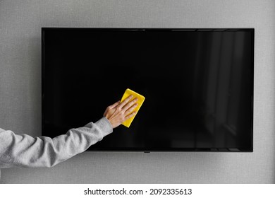 a man wipes dust from a plasma TV. man wipes the monitor general cleaning of the apartment cleaning - Shutterstock ID 2092335613