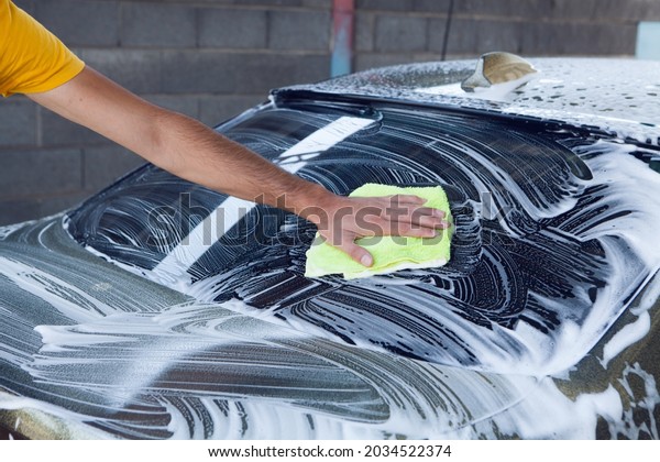 a man
wipes the foam on the car with a rag. car
wash