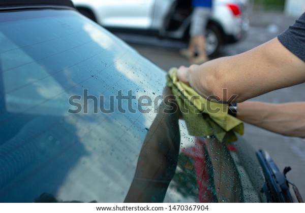 man wipes\
and polishes a car glass after\
washing.