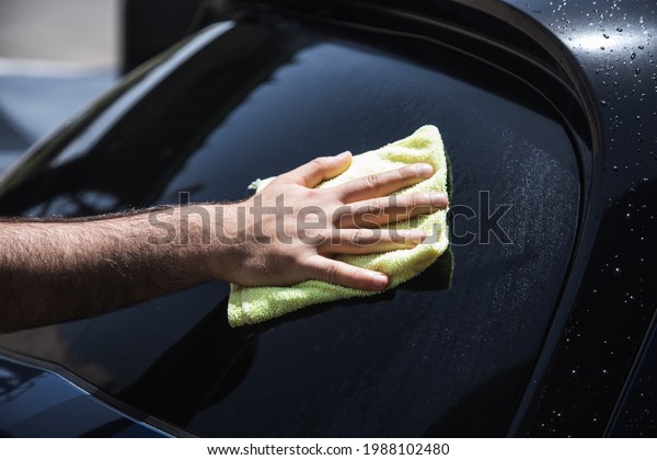 a man wipes a wet car with\
a rag