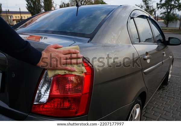 Man\
wiping the car with a cloth, car detailing\
concept.